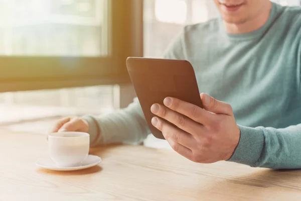 Abgeschnittene Ansicht eines Mannes, der mit eBook stopft und zu Hause eine Tasse Tee hält — Stockfoto