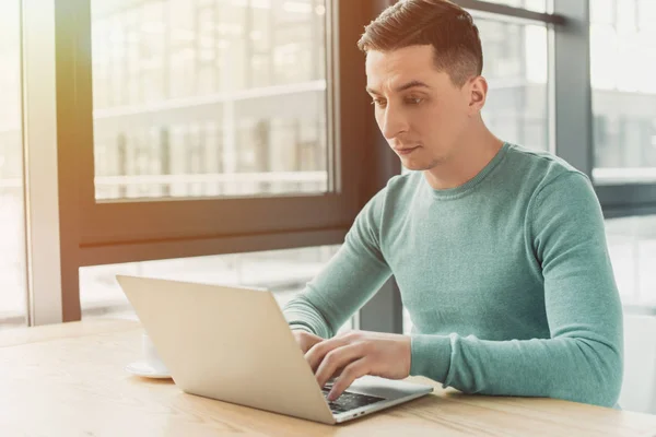 Schöner Mann tippt auf Laptop, während er zu Hause sitzt — Stockfoto