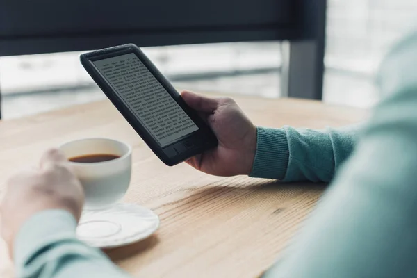 Vue recadrée de l'homme tenant tasse de thé près e-reader tout en claquant à la maison — Photo de stock