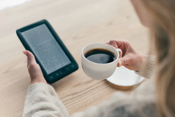 Ausgeschnittene Ansicht einer Frau, die mit E-Book stopft und Tasse mit Kaffee hält — Stockfoto