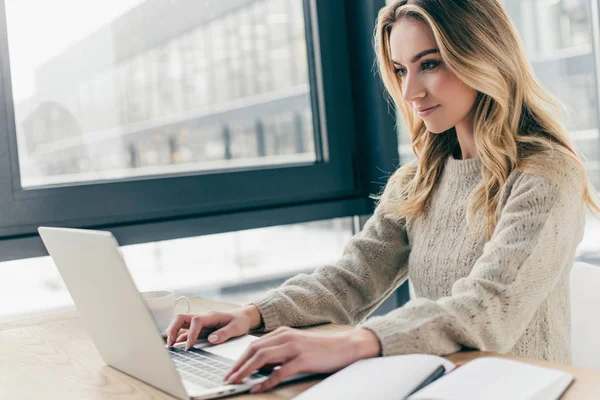 Bella donna che utilizza il computer portatile mentre seduto a casa — Foto stock