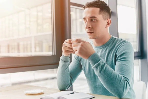 Nachdenklicher Mann hält Tasse mit Getränk im Sitzen — Stockfoto