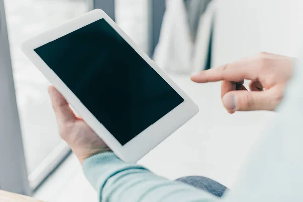 Ausgeschnittene Ansicht eines Mannes, der mit dem Finger auf ein digitales Tablet mit leerem Bildschirm in den Händen zeigt — Stockfoto