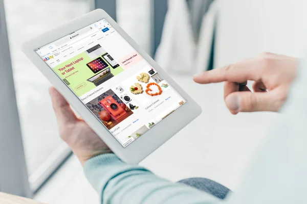 Cropped view of man holding digital tablet with ebay app on screen — Stock Photo