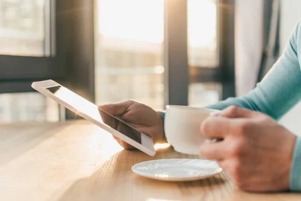 Vue recadrée de l'homme tenant tablette numérique et tasse avec boisson — Photo de stock