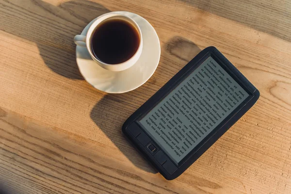 E-book noir couché près de tasse avec boisson — Photo de stock