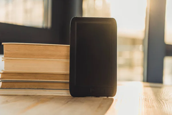 Ebook con schermo bianco vicino a libri di carta su tavolo di legno — Foto stock