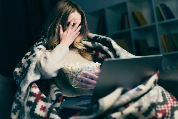 Frau schaut beängstigenden Film auf Laptop und bedeckt Gesicht mit der Hand — Stockfoto