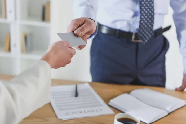 Vista recortada del hombre dando tarjeta de visita vacía a una colega - foto de stock