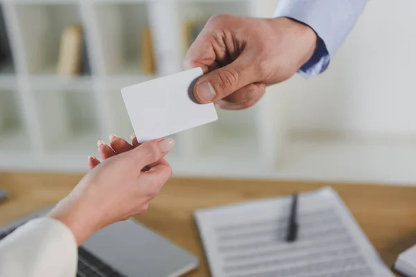 Cropped view of businessman giving empty business card to female colleague — Stock Photo