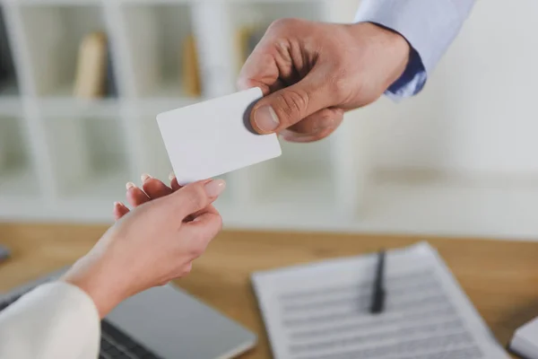 Vista recortada de hombre de negocios dando tarjeta de visita vacía a una colega — Stock Photo
