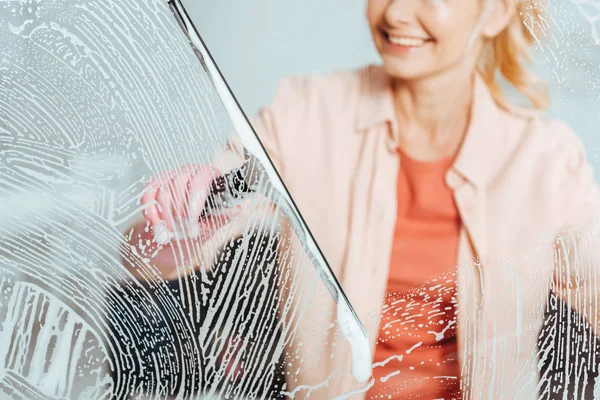 Vista cortada da mulher rindo usando limpador de vidro durante a janela de limpeza — Fotografia de Stock