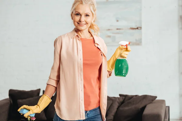 Sorridente donna anziana che tiene spray e spugna per la pulizia — Foto stock