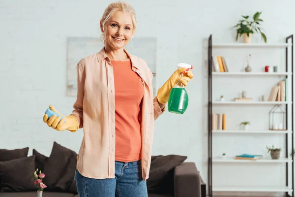 Felice donna anziana in posa con spray detergente e spugna — Foto stock