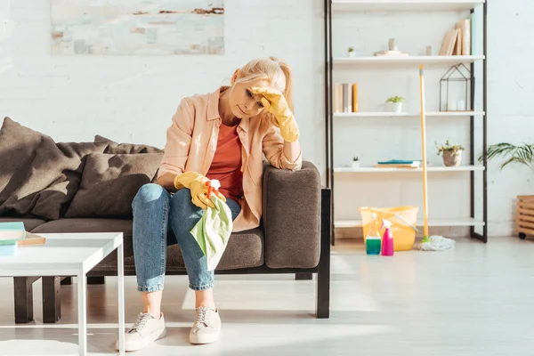 Tired senior woman with rag resting on sofa — Stock Photo