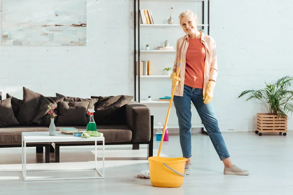 Vista completa di donna anziana sorridente con secchio e pavimento di pulizia mop — Foto stock