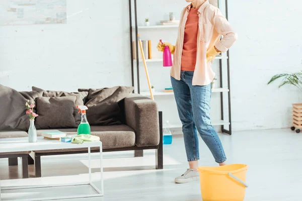 Partial view of woman in jeans posing with cleaning supplies — Stock Photo