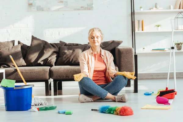 Senior woman sitting in lotus pose during housework — Stock Photo