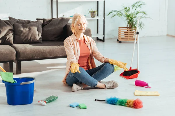 Femme âgée détendue assise dans la pose de lotus après les travaux ménagers — Photo de stock