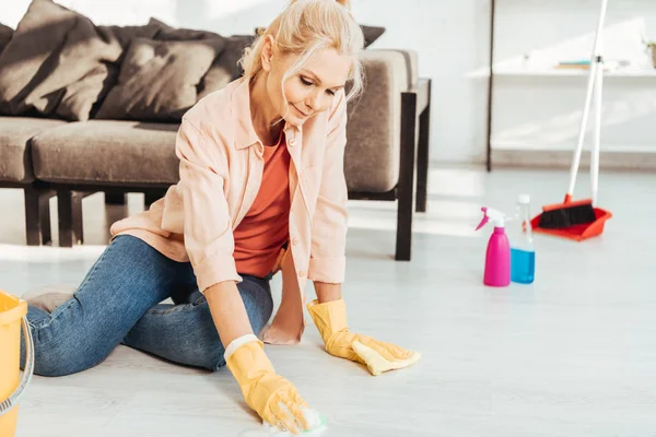 Mulher sênior em luvas de borracha amarela chão de limpeza com pano — Fotografia de Stock