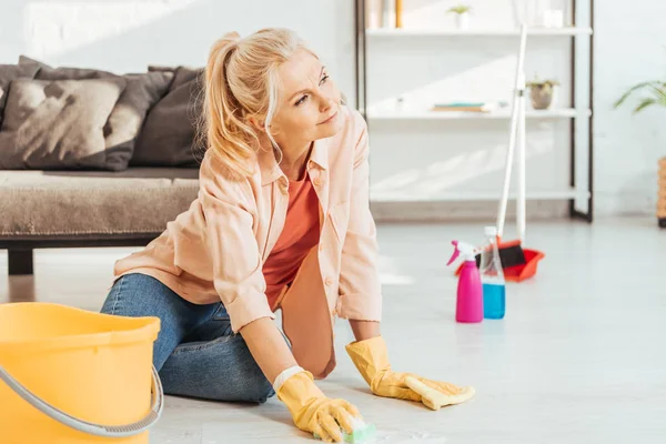 Sonhador sênior mulher limpeza chão com pano — Fotografia de Stock