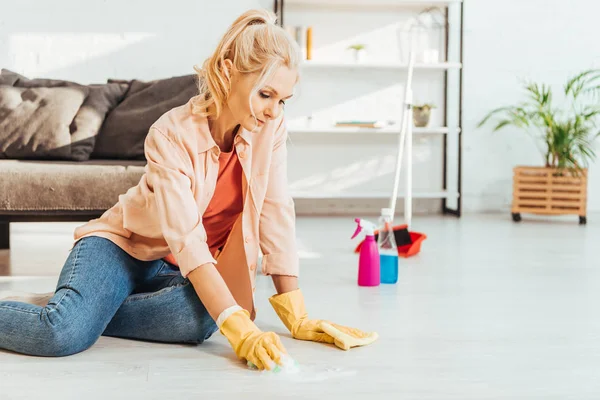 Seniorin in Jeans putzt Fußboden mit Lappen — Stockfoto