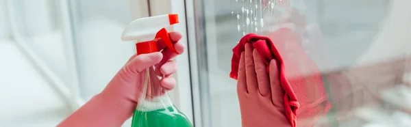 Cropped view of woman in pink rubber gloves cleaning window with spray — Stock Photo