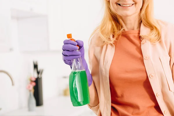 Cropped view of smiling senior woman in rubber glove holding spray — Stock Photo