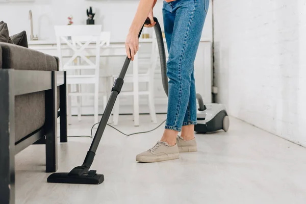 Ausgeschnittene Ansicht einer Frau, die Boden mit Staubsauger reinigt — Stockfoto