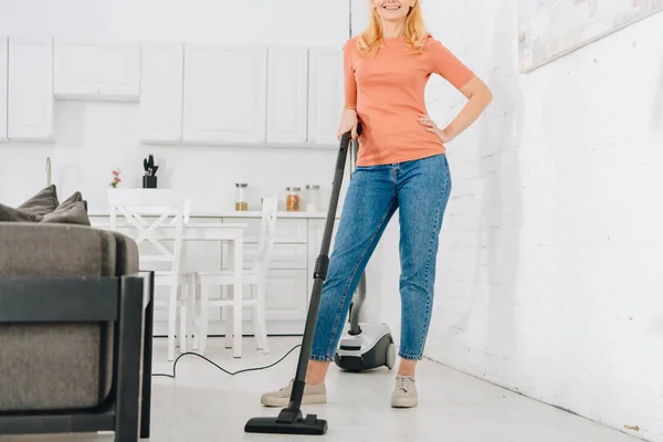 Vista parziale della donna gioiosa pulizia casa con aspirapolvere — Foto stock