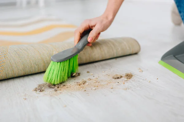 Recortado tiro de mujer barriendo piso con cepillo verde - foto de stock