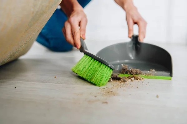 Vista parcial de la mujer con cepillo y piso de limpieza de cucharada debajo de la alfombra - foto de stock