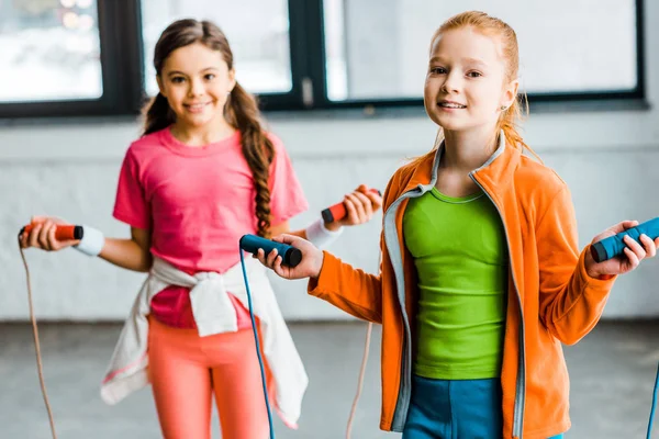 Niños felices posando con cuerdas de saltar en el gimnasio — Stock Photo