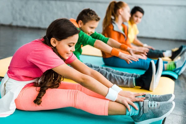 Groupe d'enfants s'étirant dans la salle de gym ensemble — Photo de stock