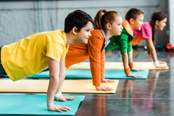 Preteen kids doing plank exercise in gym — Stock Photo