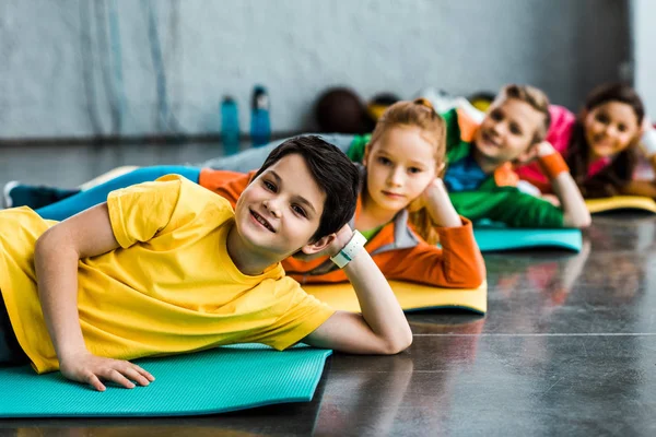 Bambini gioiosi sdraiati su tappeti fitness e guardando la fotocamera — Foto stock