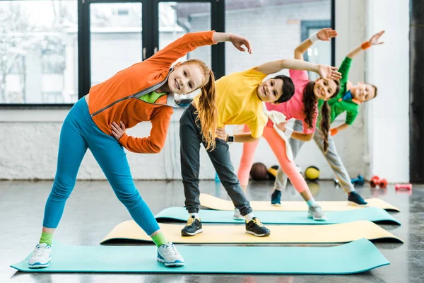 Sorrindo crianças pré-adolescentes fazendo exercício esportivo juntos — Fotografia de Stock