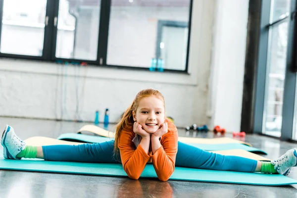 Adorable smiling kid doing twine in gym — Stock Photo