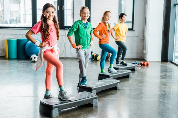 Группа детей, использующих ступенчатые платформы в тренажерном зале — стоковое фото