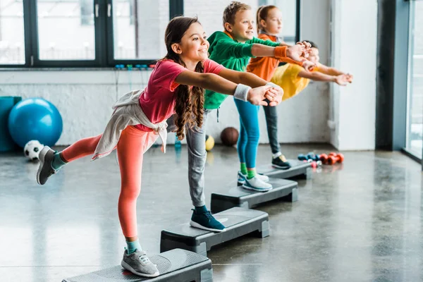 Niños alegres haciendo ejercicios con plataformas de paso - foto de stock