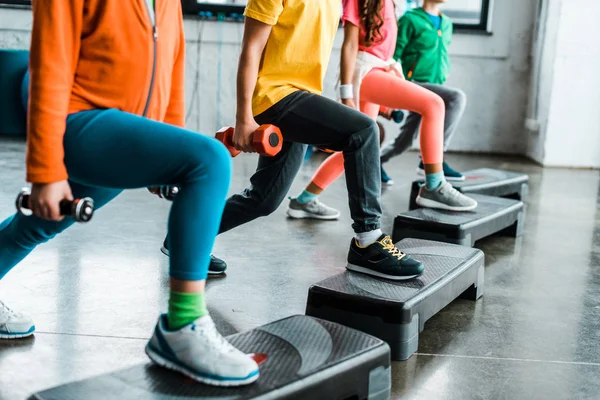 Cropped view of kids with dumbbells training with step platforms — Stock Photo