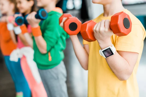 Cropped view of kids training with dumbbells — Stock Photo