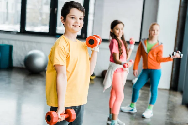 Group of kids training with dumbbells in gym — Stock Photo