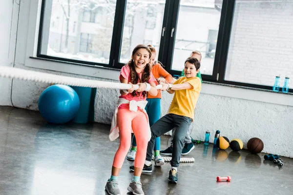 Bambini eccitati che giocano a tiro alla fune in palestra — Foto stock