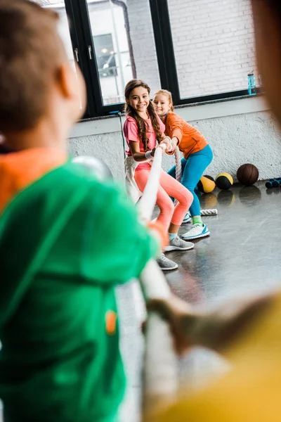 Enfants enthousiastes jouant remorqueur de guerre dans la salle de gym — Photo de stock