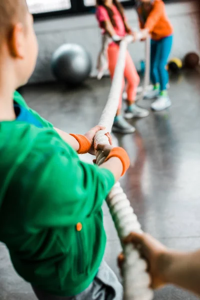 Niños jugando tirón de la guerra en el gimnasio - foto de stock