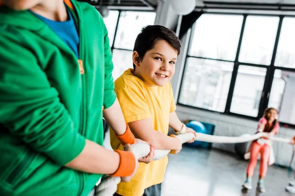 Preteen children pulling rope in gym with smile — Stock Photo
