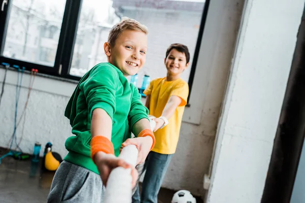 Laughing boys playing tug of war in gym — Stock Photo