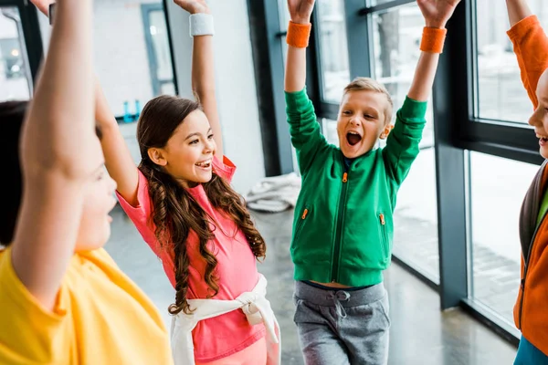 Blissful kids posing with hands up after training in gym — Stock Photo