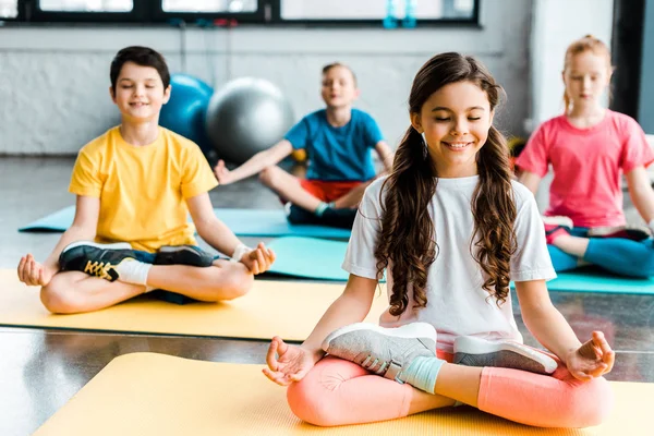 Pleased preteen kids stretching on fitness mats — Stock Photo